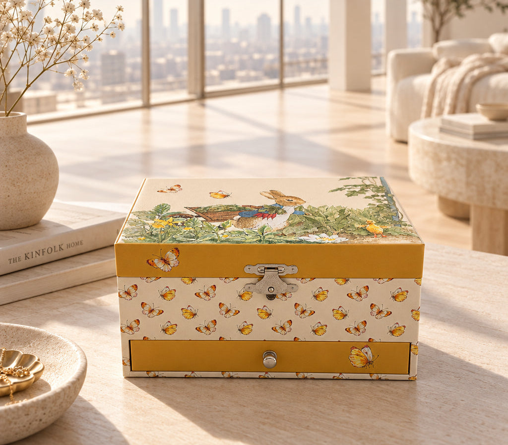 Boîte à bijoux musicale Peter Rabbit à décor papillons, posée sur une table dans un salon lumineux